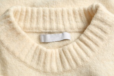 Blank clothing label on white cashmere sweater, top view