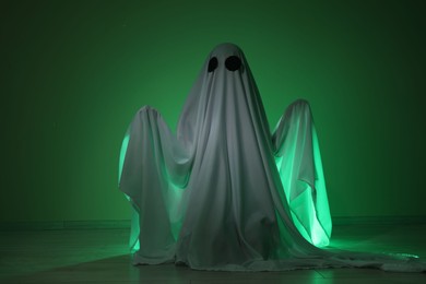 Creepy ghost. Woman covered with sheet in green light