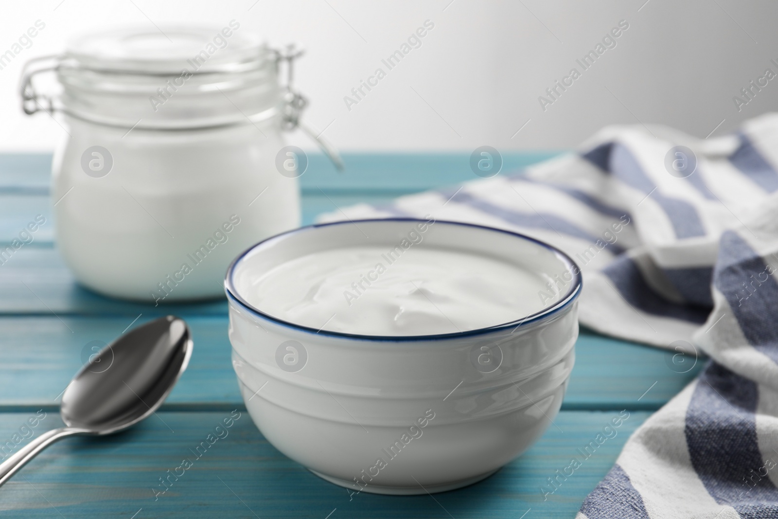 Photo of Tasty organic yogurt on light blue wooden table