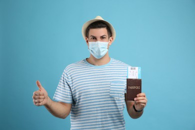 Photo of Male tourist in protective mask holding passport with ticket on turquoise background