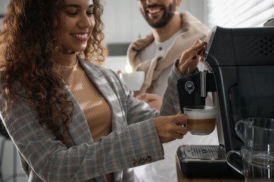 African American woman preparing fresh aromatic coffee with modern machine in office