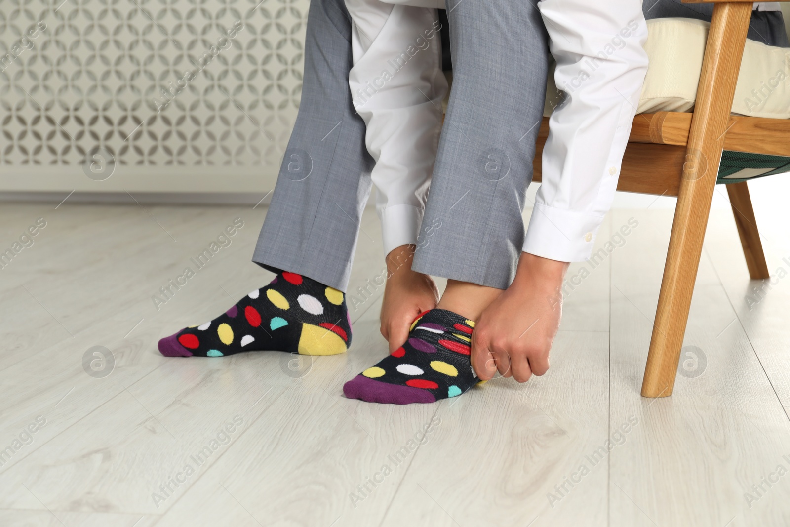 Photo of Man putting on colorful socks indoors, closeup