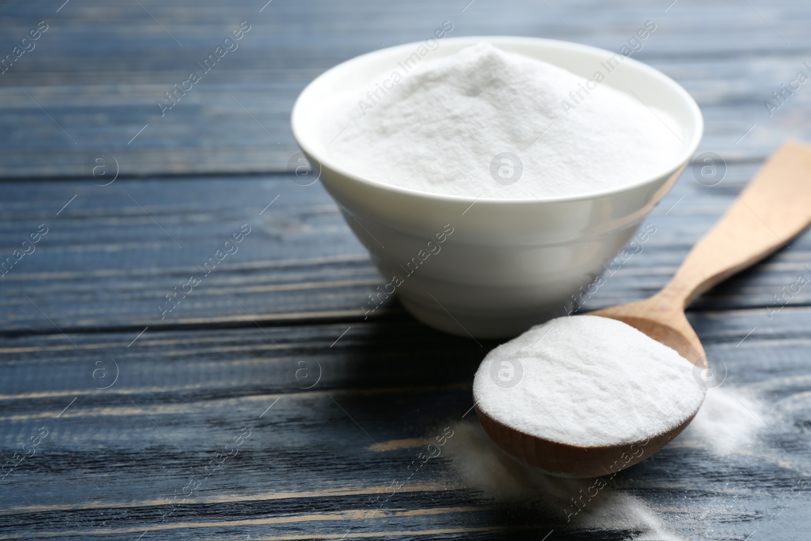 Photo of Baking soda in bowl on blue wooden table