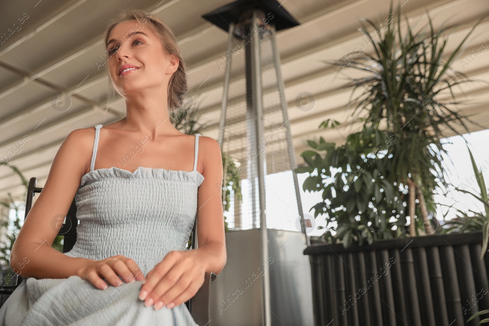 Photo of Beautiful young woman sitting on indoor terrace in cafe, space for text