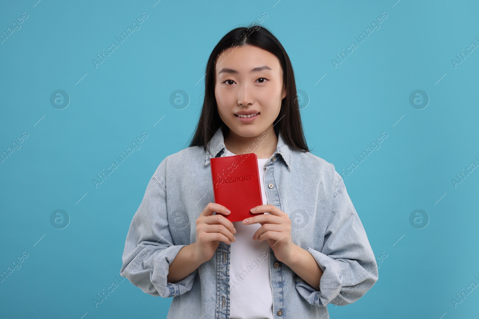 Photo of Immigration. Happy woman with passport on light blue background