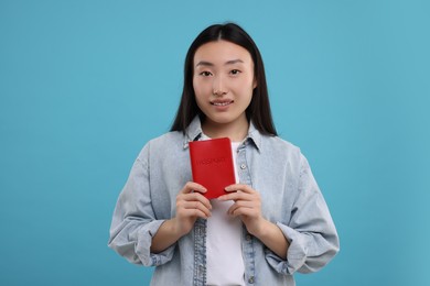 Immigration. Happy woman with passport on light blue background