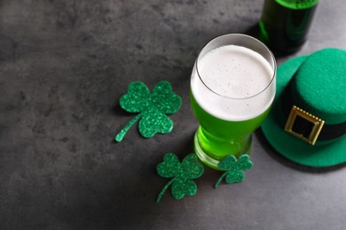 Photo of St. Patrick's day celebration. Green beer, leprechaun hat and decorative clover leaves on grey table. Space for text