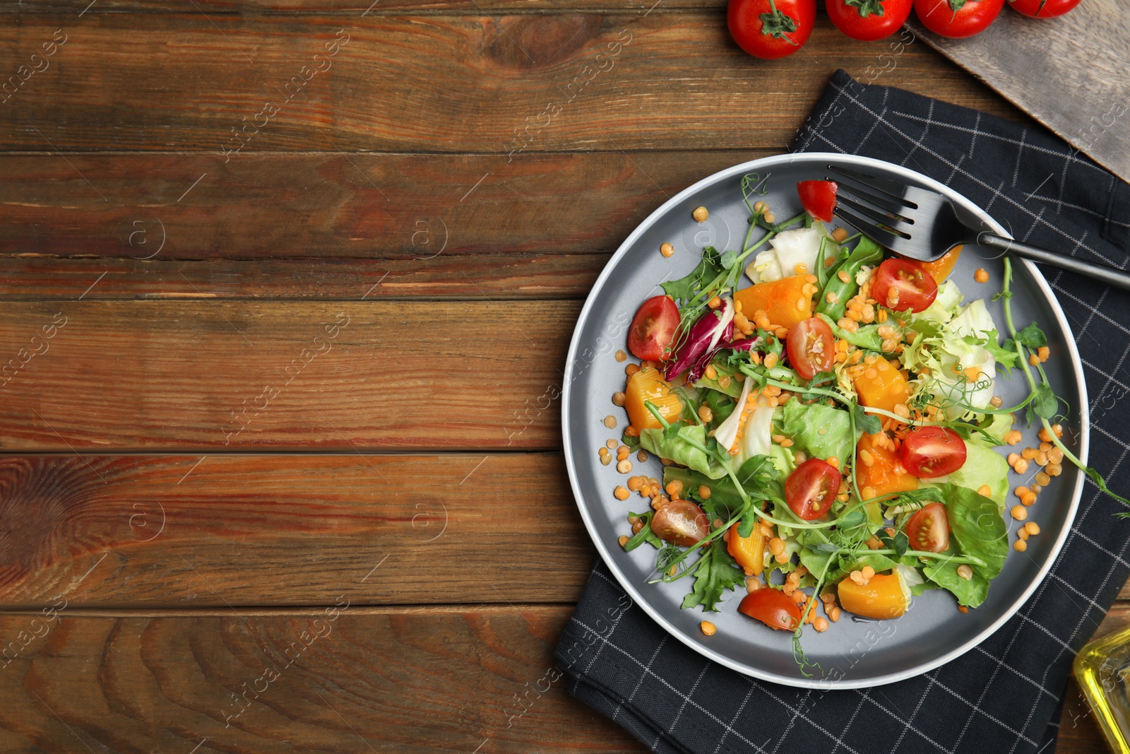 Photo of Delicious salad with lentils and vegetables served on wooden table, flat lay. Space for text