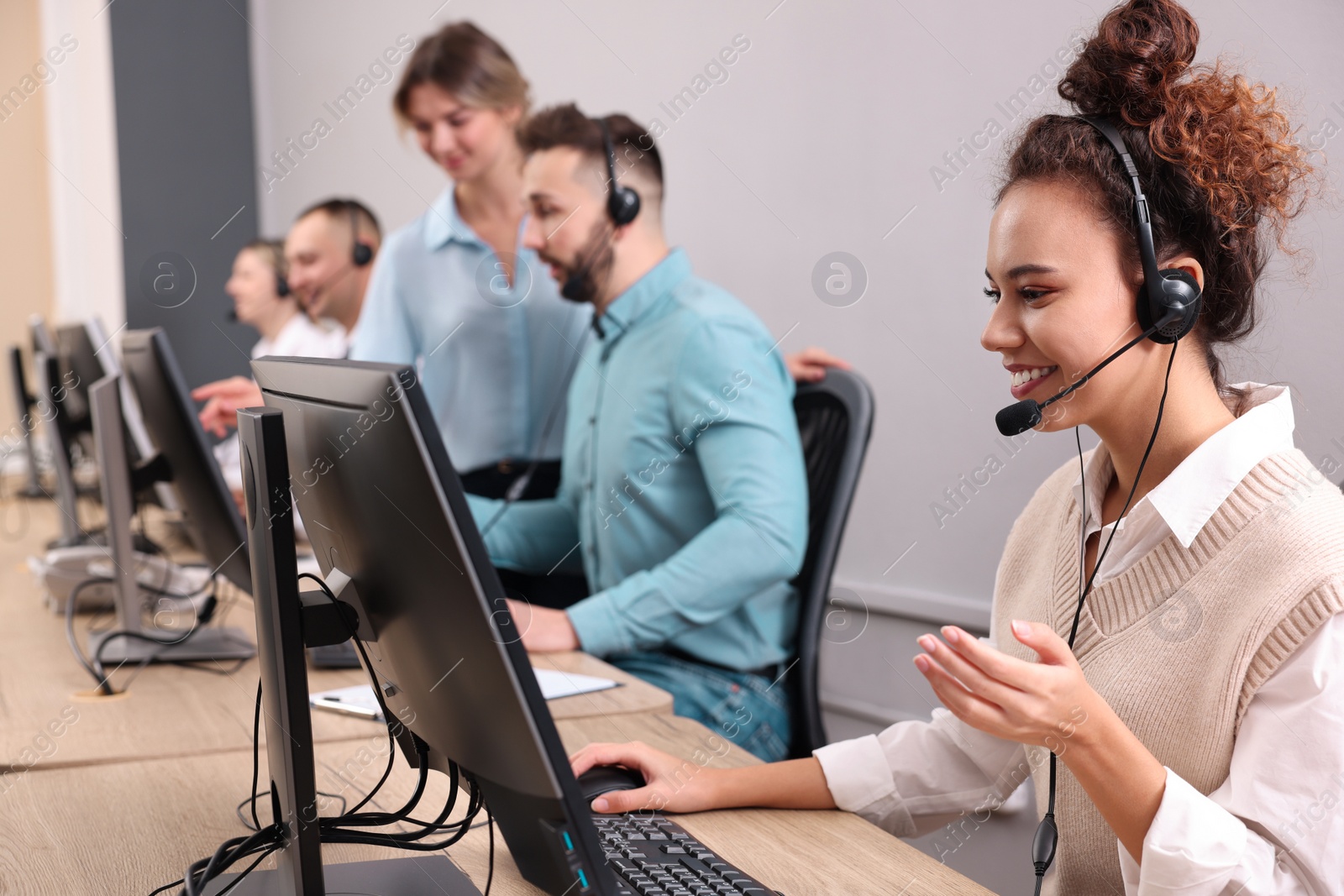 Photo of Call center operators working in modern office, focus on African American woman with headset