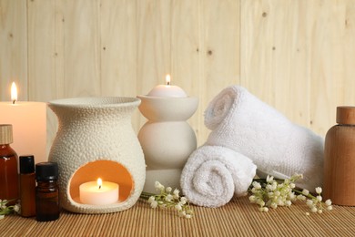 Aromatherapy. Scented candles, bottles, flowers and towels on bamboo mat