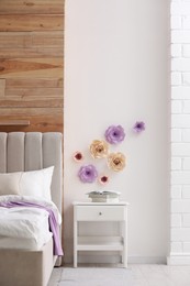 Stylish bedroom interior with floral decor and white nightstand