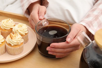 Photo of Woman with cup of hot drink in bed, closeup