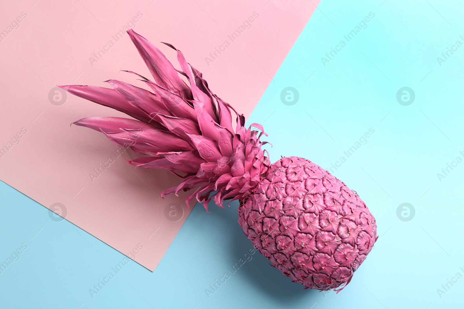 Photo of Pink pineapple on color background, top view. Creative concept