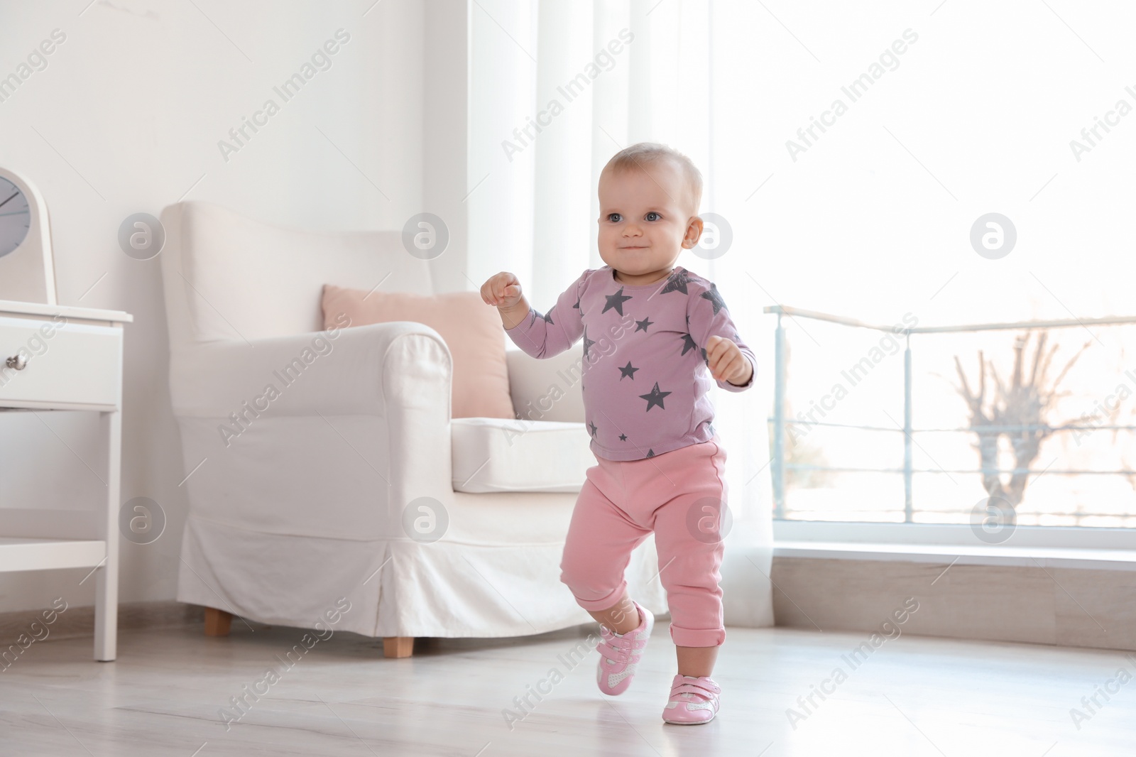 Photo of Cute baby girl walking in room at home