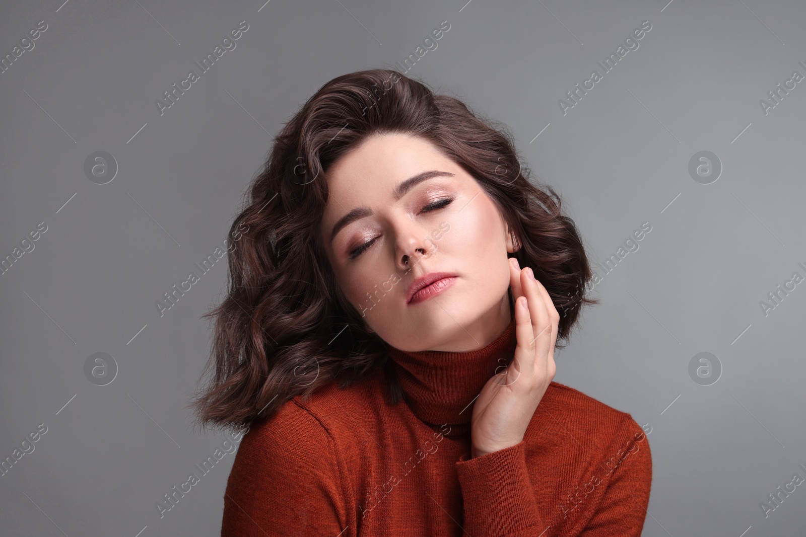 Photo of Portrait of beautiful young woman with wavy hairstyle on grey background