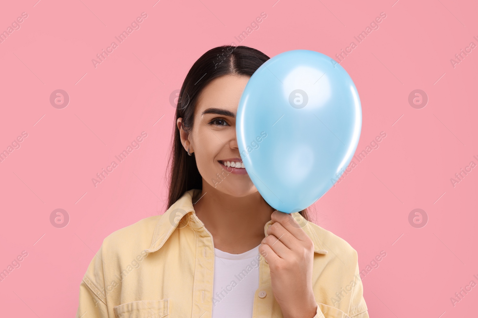 Photo of Woman with light blue balloon on pink background