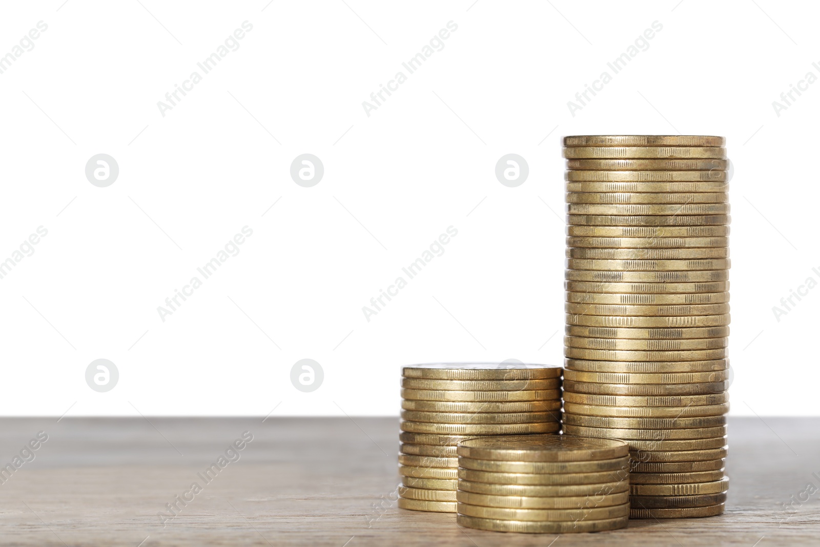 Photo of Many golden coins stacked on wooden table against white background, space for text