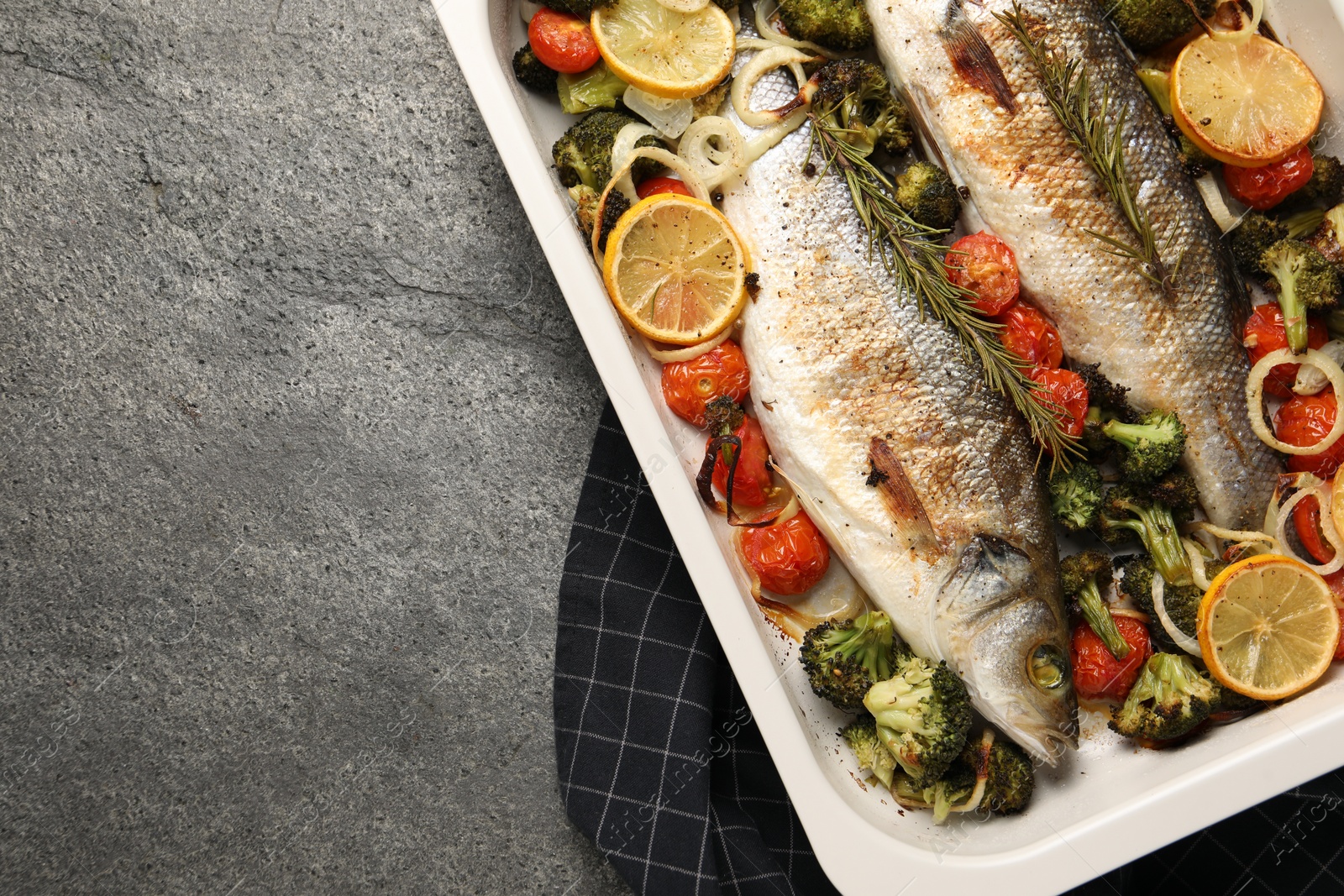 Photo of Delicious fish with vegetables and lemon in baking dish on grey textured table, top view. Space for text