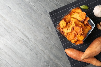 Photo of Flat lay composition with bowl of sweet potato chips on grey table. Space for text