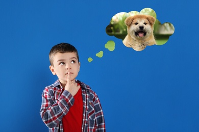 Image of Little boy dreaming about cute puppy, blue background