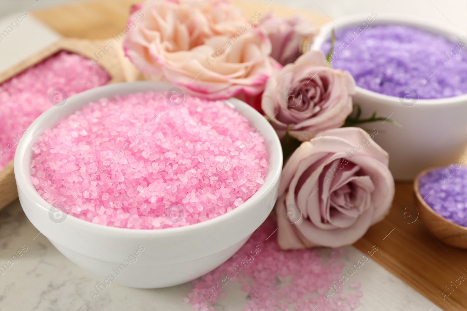 Photo of Sea salt and beautiful roses on light grey marble table, closeup