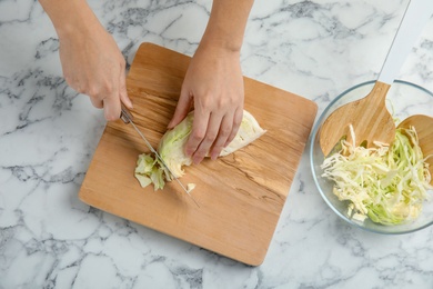 Photo of Woman cutting ripe cabbage at table, top view