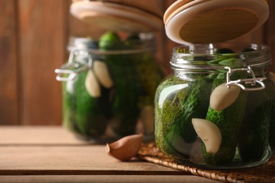 Glass jars with fresh cucumbers ready for canning on wooden table, space for text