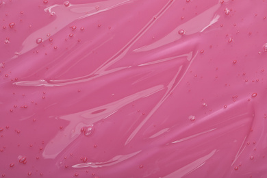 Pure transparent cosmetic gel on pink background, closeup