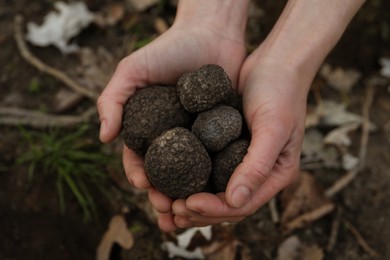 Woman holding fresh truffles in hands outdoors, closeup