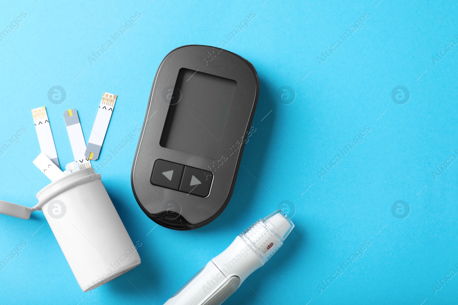 Photo of Digital glucometer, lancet pen and test strips on light blue background, flat lay with space for text. Diabetes control