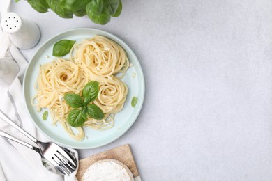 Photo of Delicious pasta with brie cheese and basil leaves served on light grey table, flat lay. Space for text