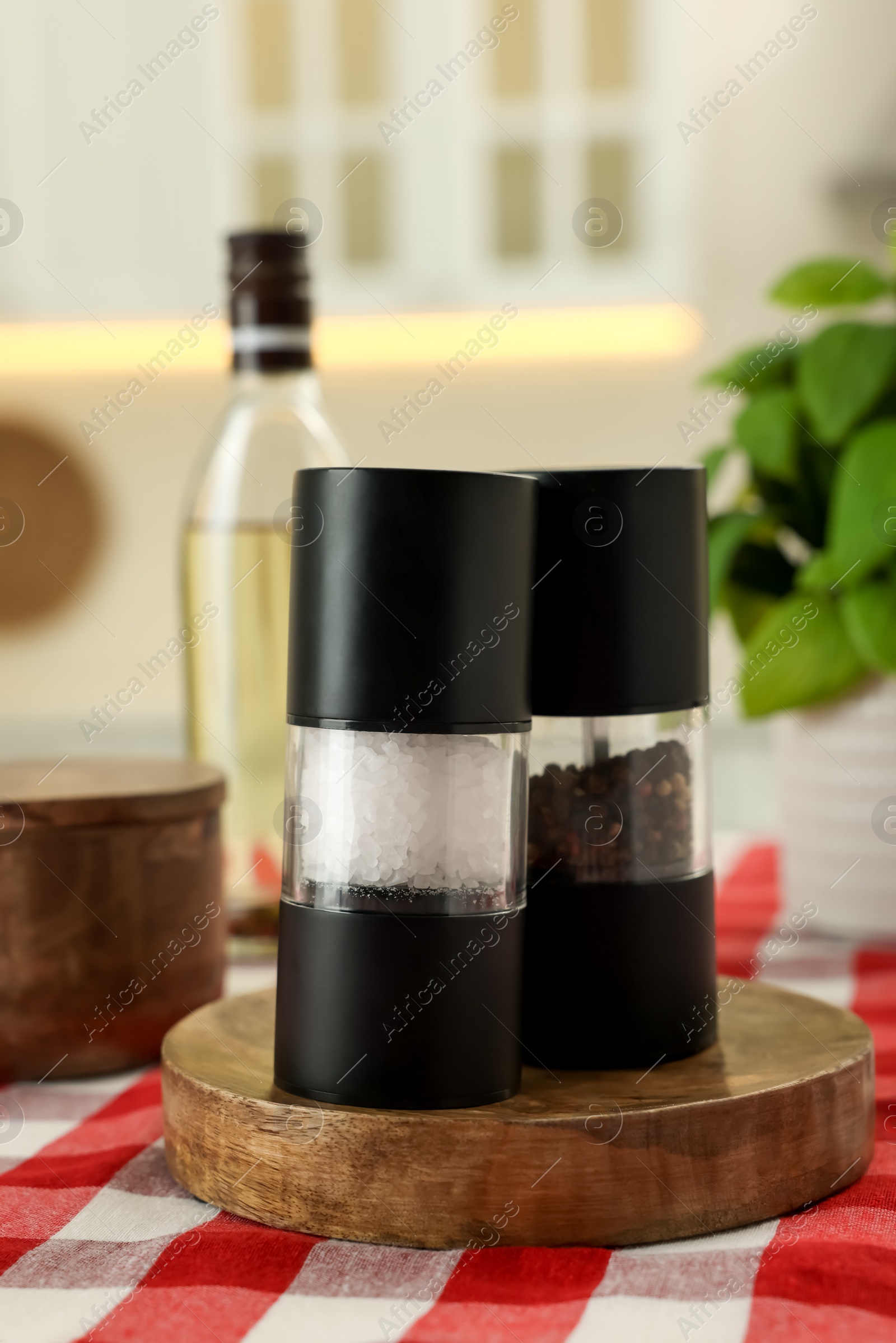 Photo of Salt and pepper shakers with bottle on table indoors