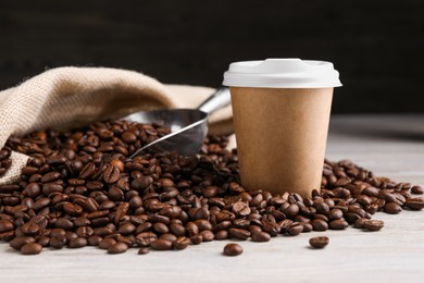 Photo of Coffee to go. Paper cup, roasted beans and scoop on light table