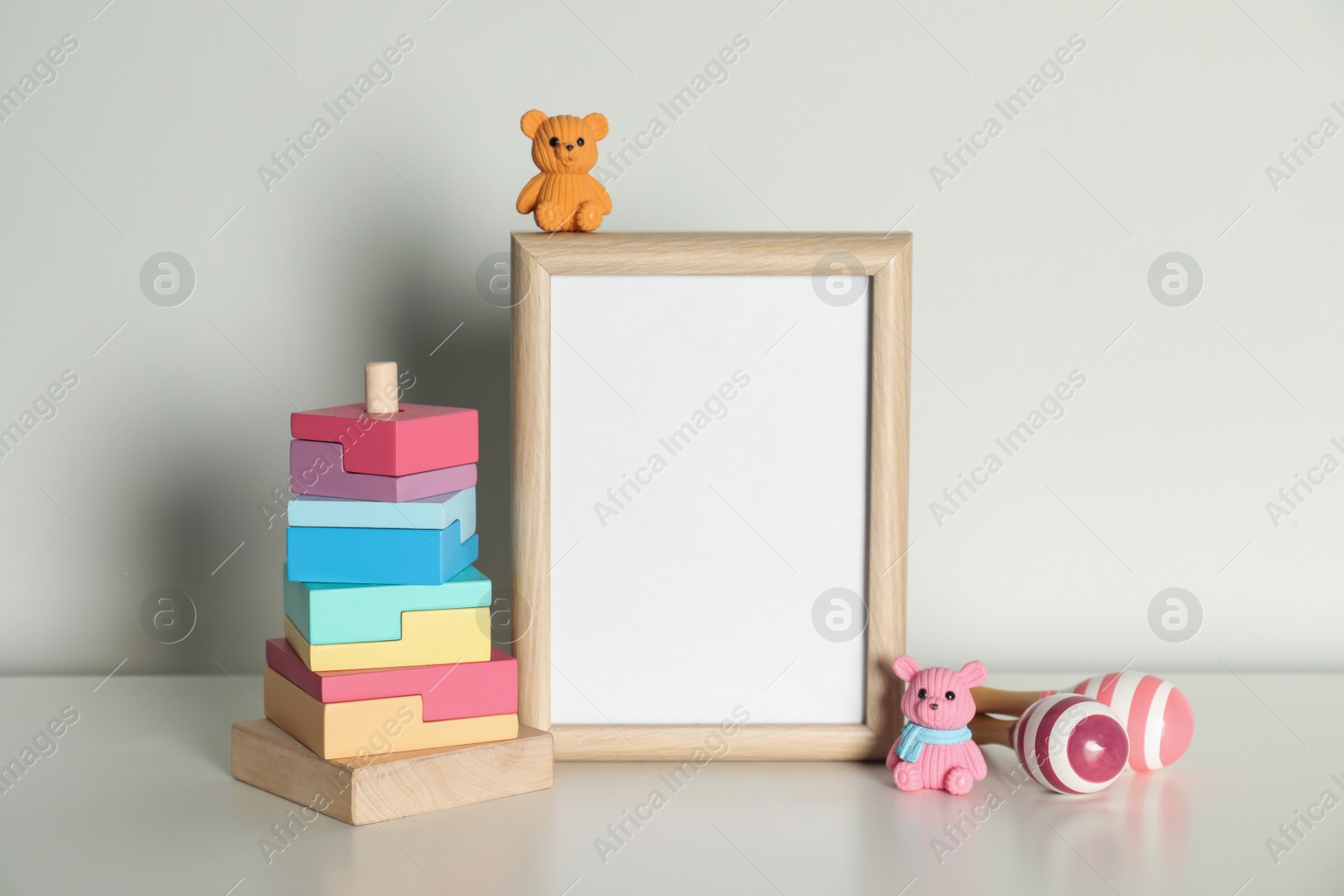 Photo of Composition with cute toys and frame on table against light background. Children's room interior elements