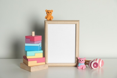 Photo of Composition with cute toys and frame on table against light background. Children's room interior elements