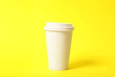 Takeaway paper coffee cup on yellow background