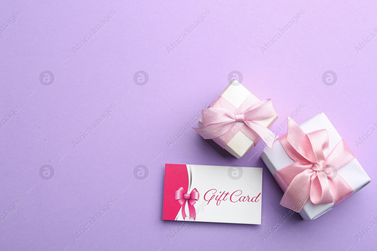 Photo of Gift card and presents on violet background, flat lay. Space for text