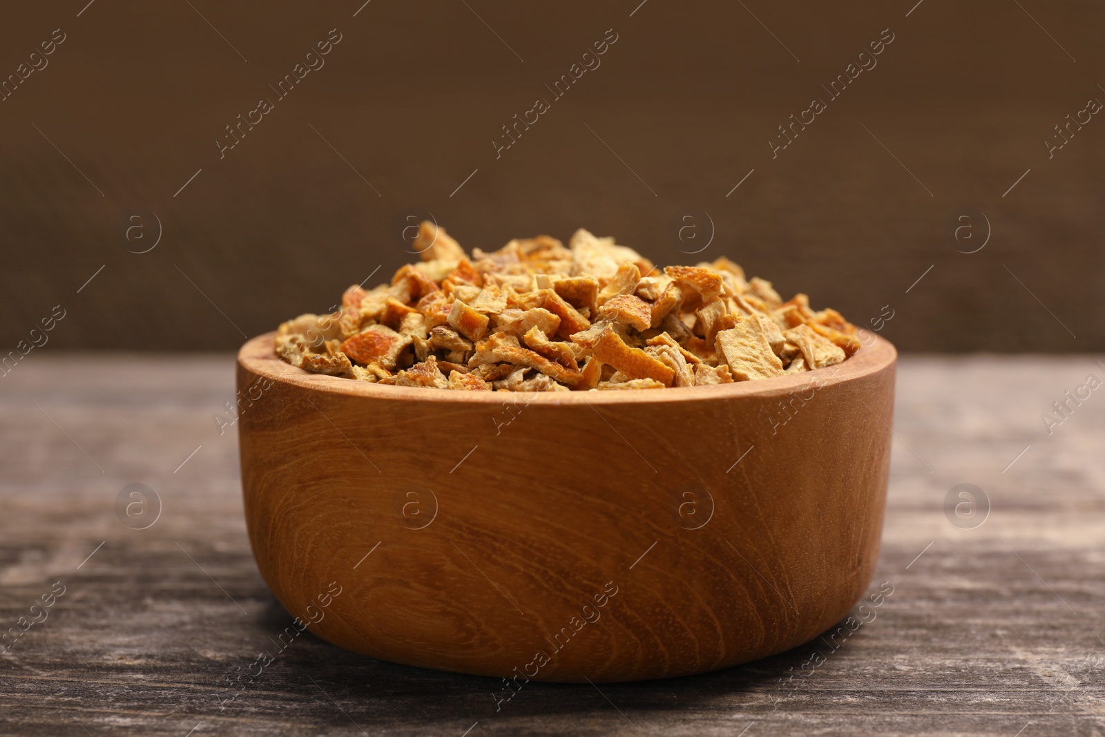 Photo of Bowl of dried orange zest seasoning on wooden table