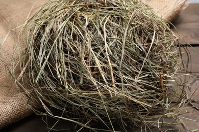 Burlap sack with dried hay on wooden table, closeup