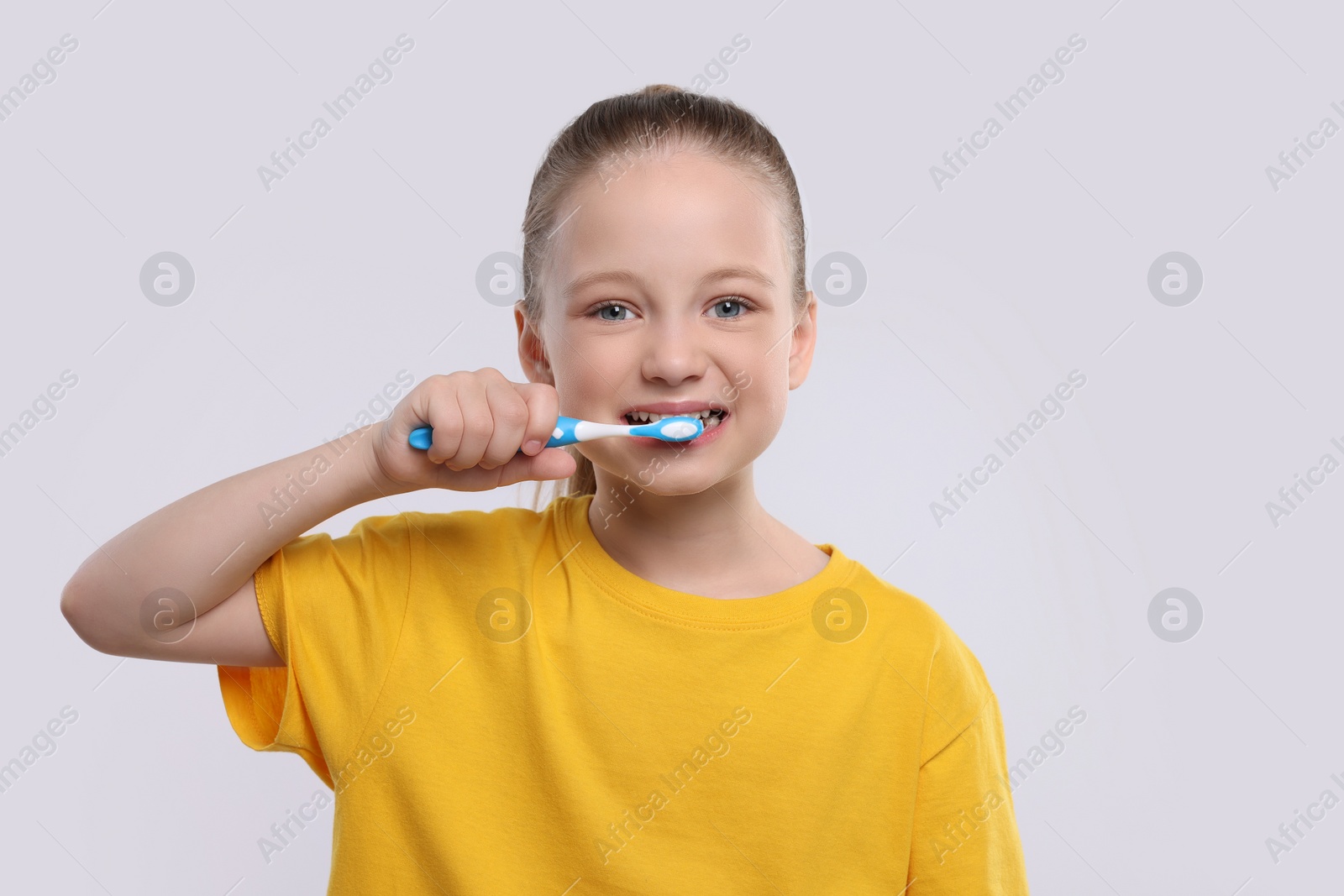 Photo of Happy girl brushing her teeth with toothbrush on white background