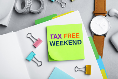 Image of Note with text TAX FREE WEEKEND and stationery on grey table, flat lay