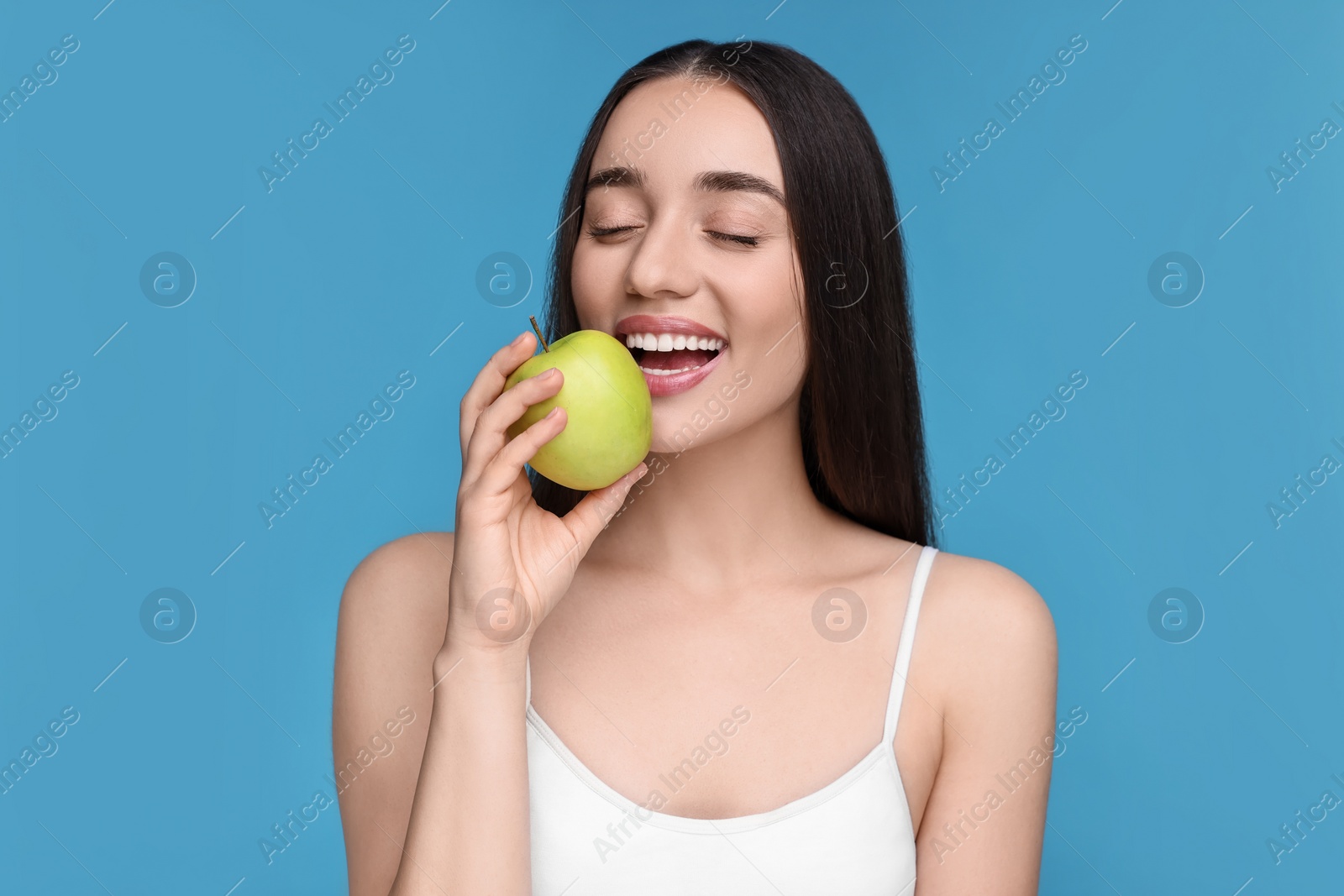 Photo of Beautiful young woman with apple on light blue background