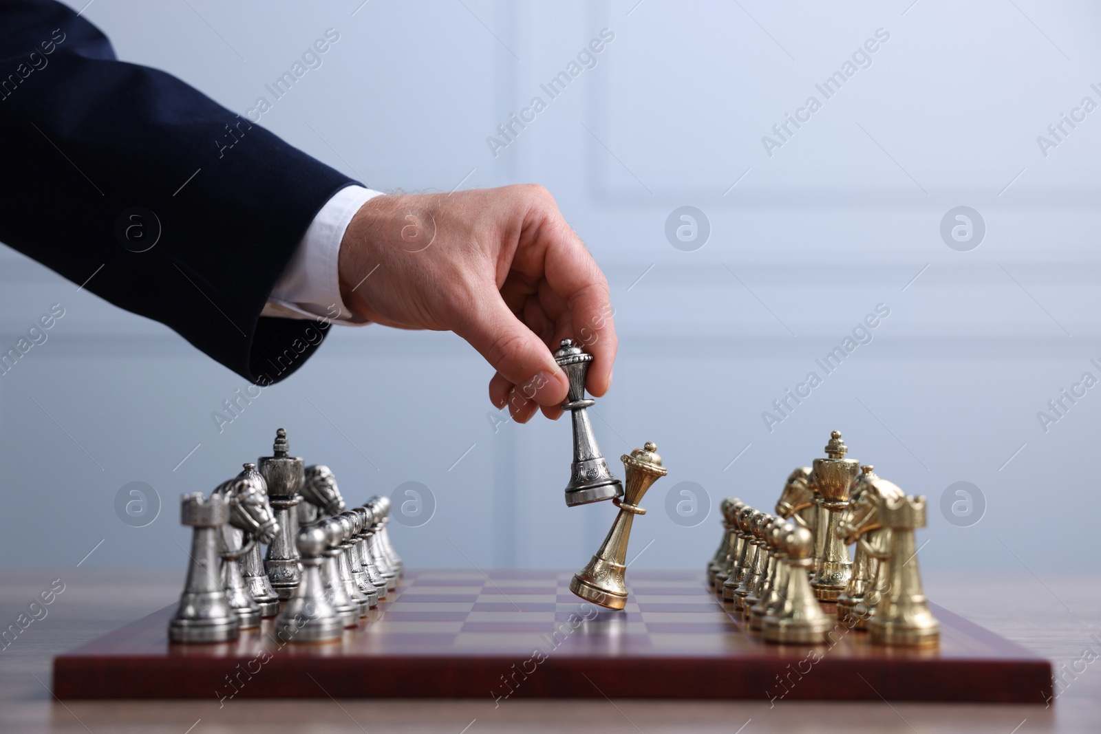 Photo of Man with bishop game piece playing chess on checkerboard at table indoors, closeup