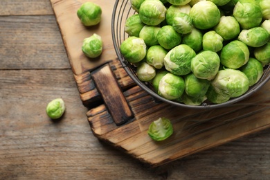 Photo of Metal basket with fresh Brussels sprouts on wooden background, top view. Space for text