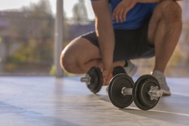 Photo of Male athlete with adjustable dumbbells indoors. Space for text