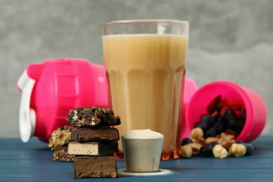 Different energy bars, protein cocktail and powder on blue wooden table