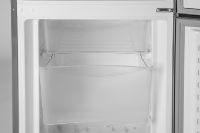 Modern open refrigerator with empty shelves, closeup