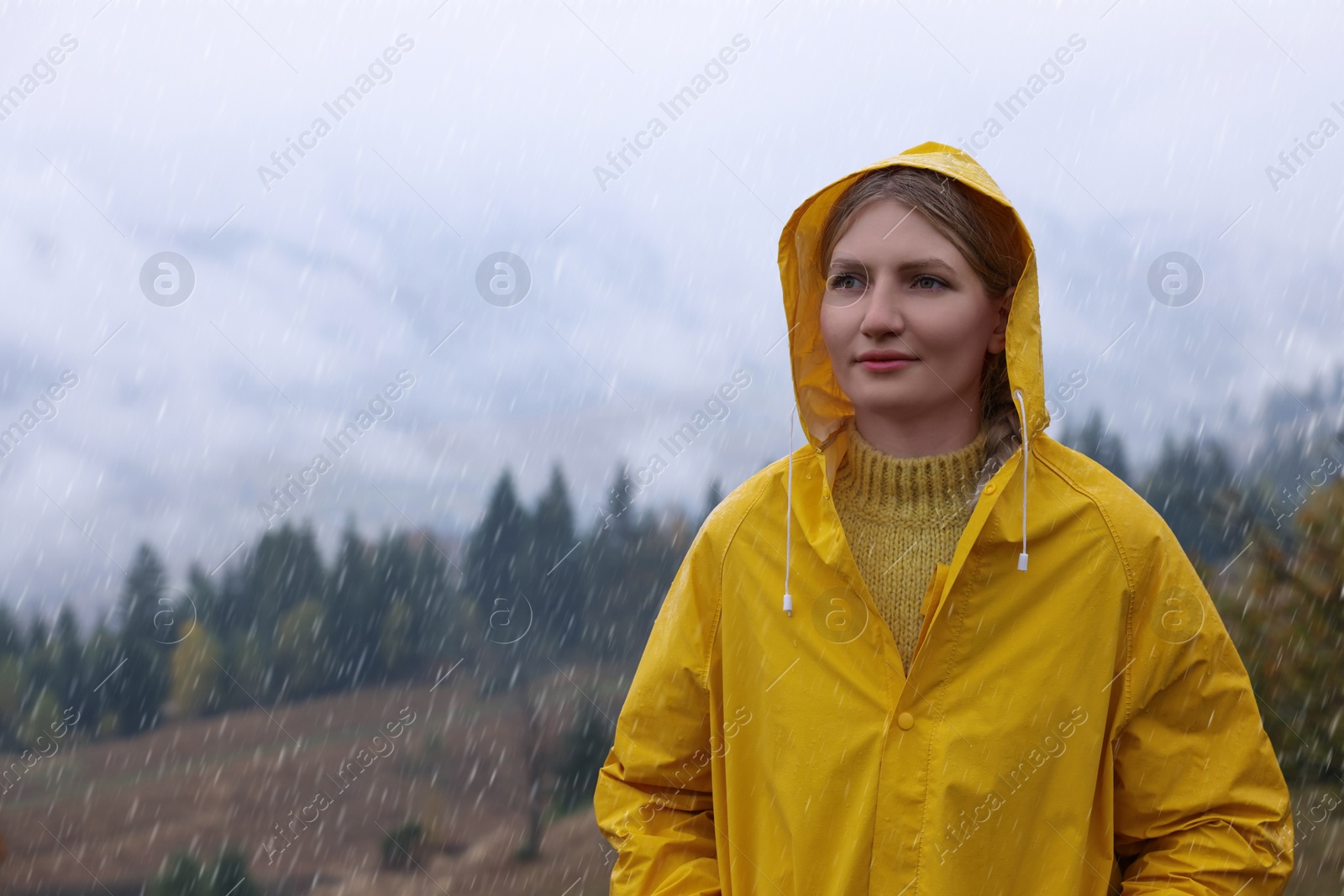 Photo of Young woman in raincoat enjoying mountain landscape under rain