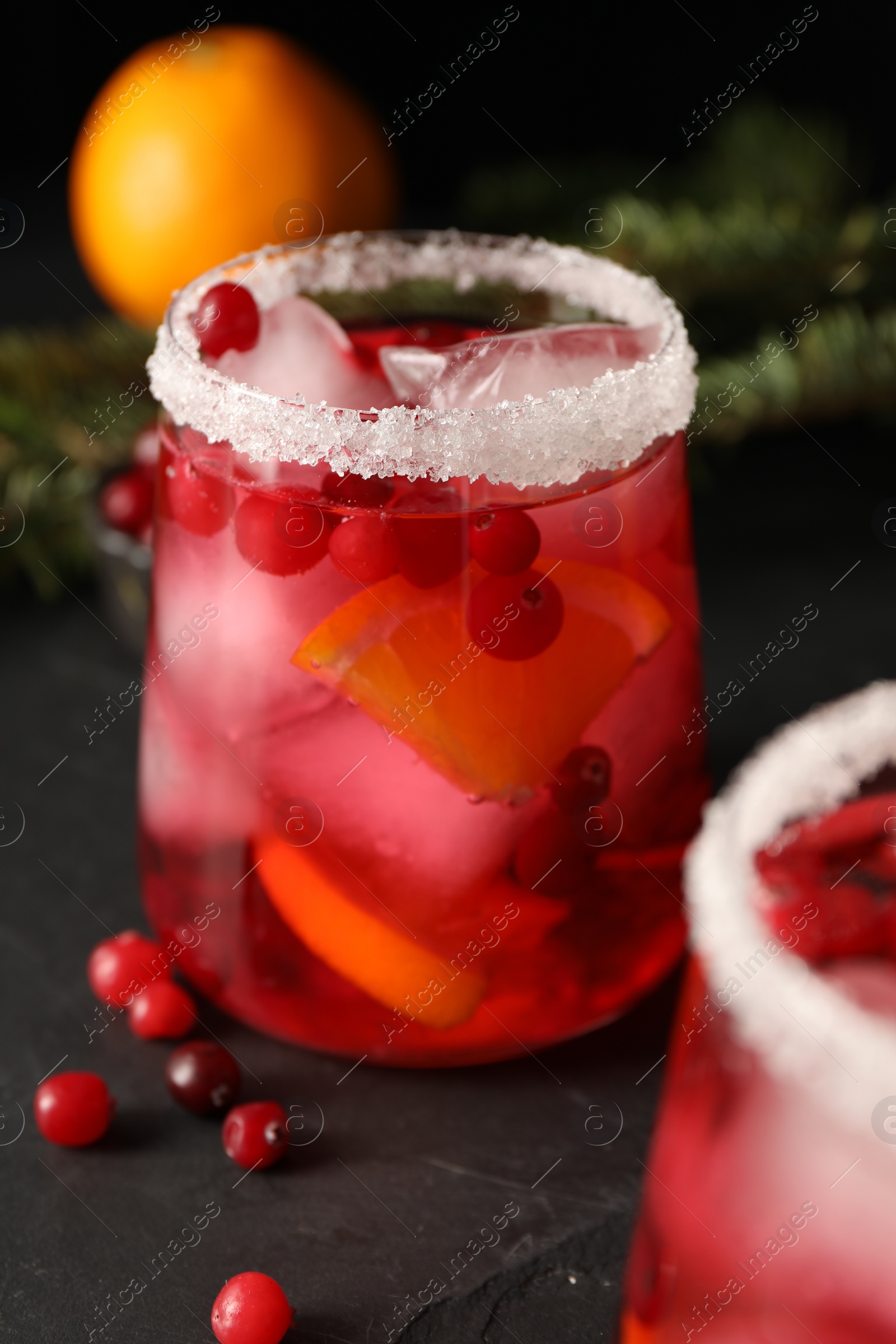Photo of Tasty cranberry cocktail with ice cubes in glass on dark gray table, closeup