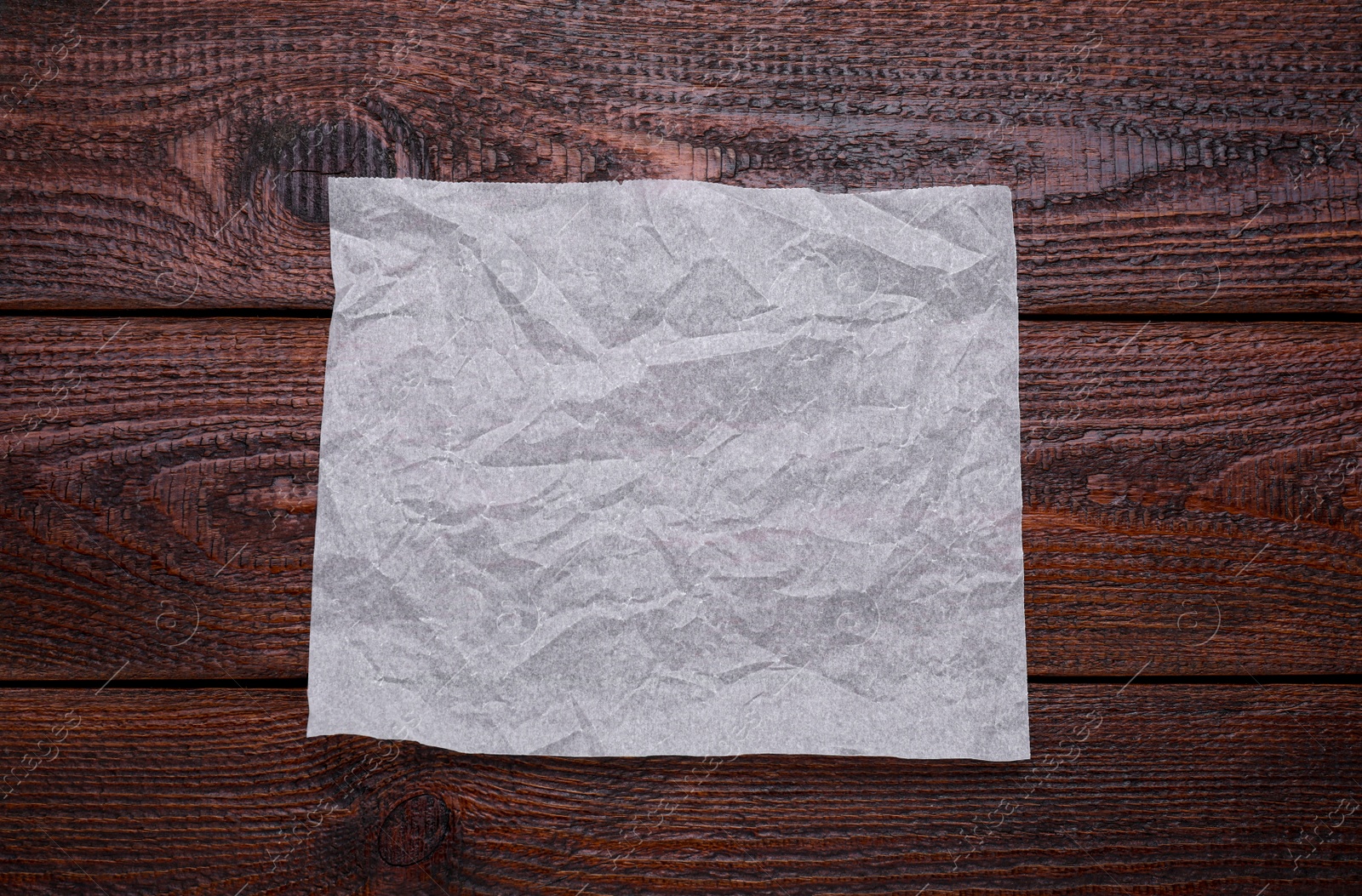 Photo of Sheet of baking paper on wooden table, top view
